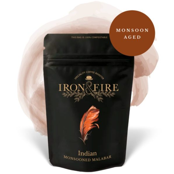 The Iron & Fire Indian Monsooned Malabar AA Coffee Beans come in a black, 100% compostable bag with an orange feather design. It is medium-bodied and labeled Monsoon Aged, making your espresso not only flavorful but also eco-friendly.