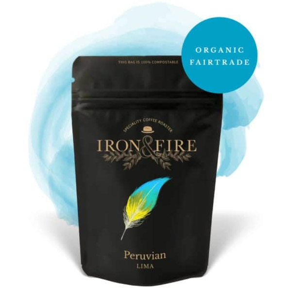 A black Iron & Fire coffee bag features a colorful feather design and Peruvian Lima label, with a blue badge indicating organic Fair Trade coffee, set against a light blue splash.